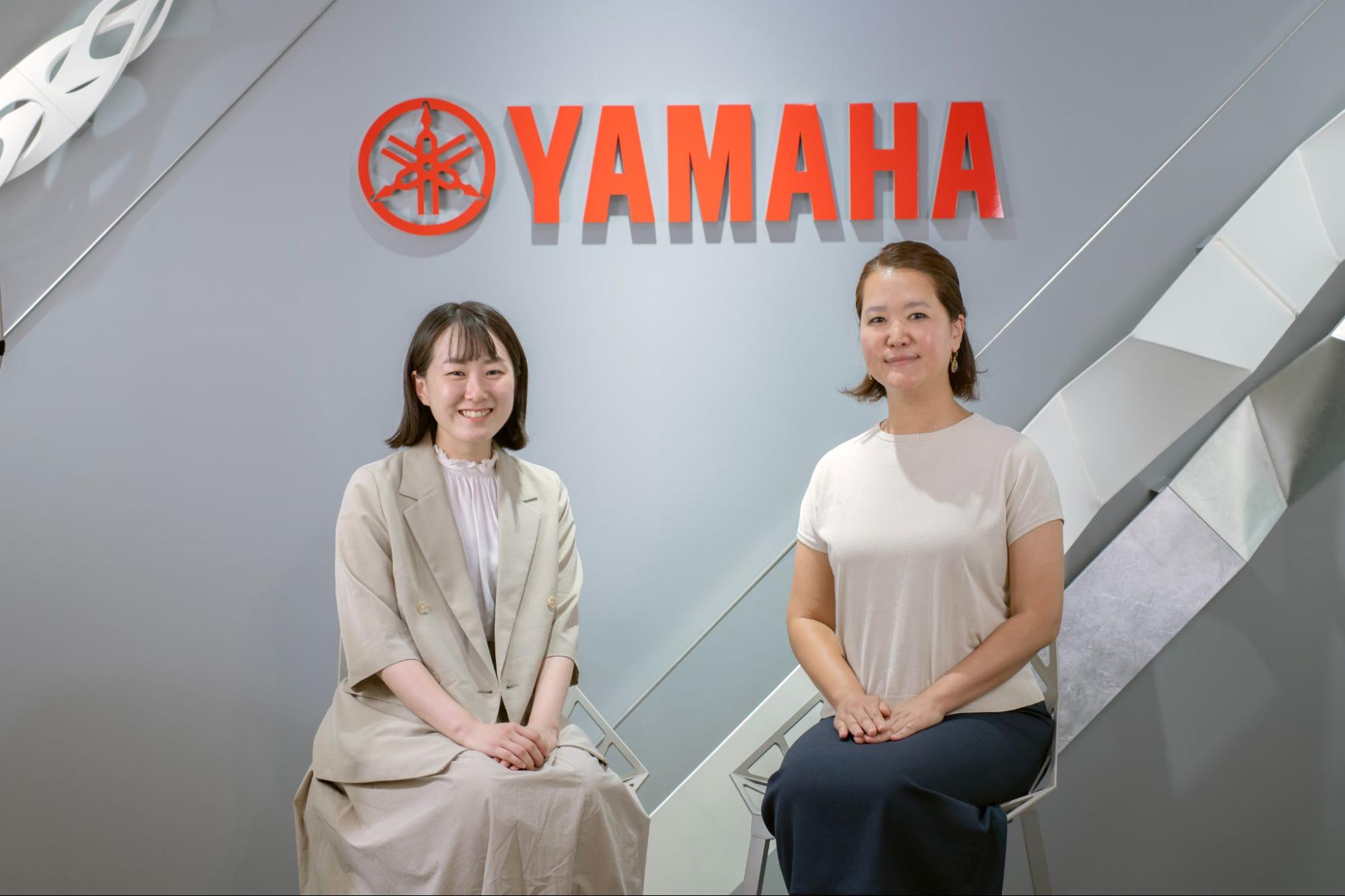 YAMAHAロゴの前に座るヤマハ発動機株式会社の木村様と片山様